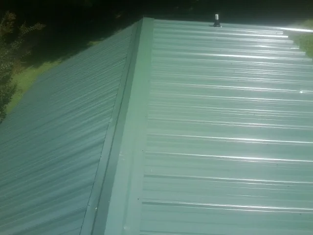 New green metal panels meeting at the ridge of a roof — Flat Roof Repair work by our crew in Homosassa