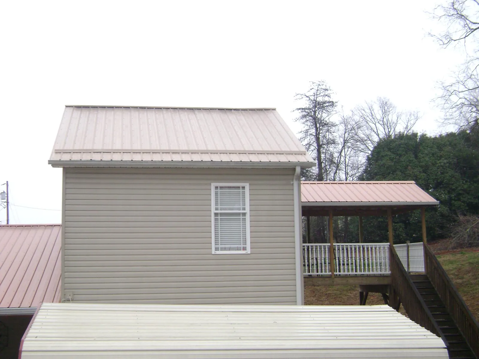 Tan metal roofs on a two story addition and attached porch, from a Roof Replacement job in Homosassa